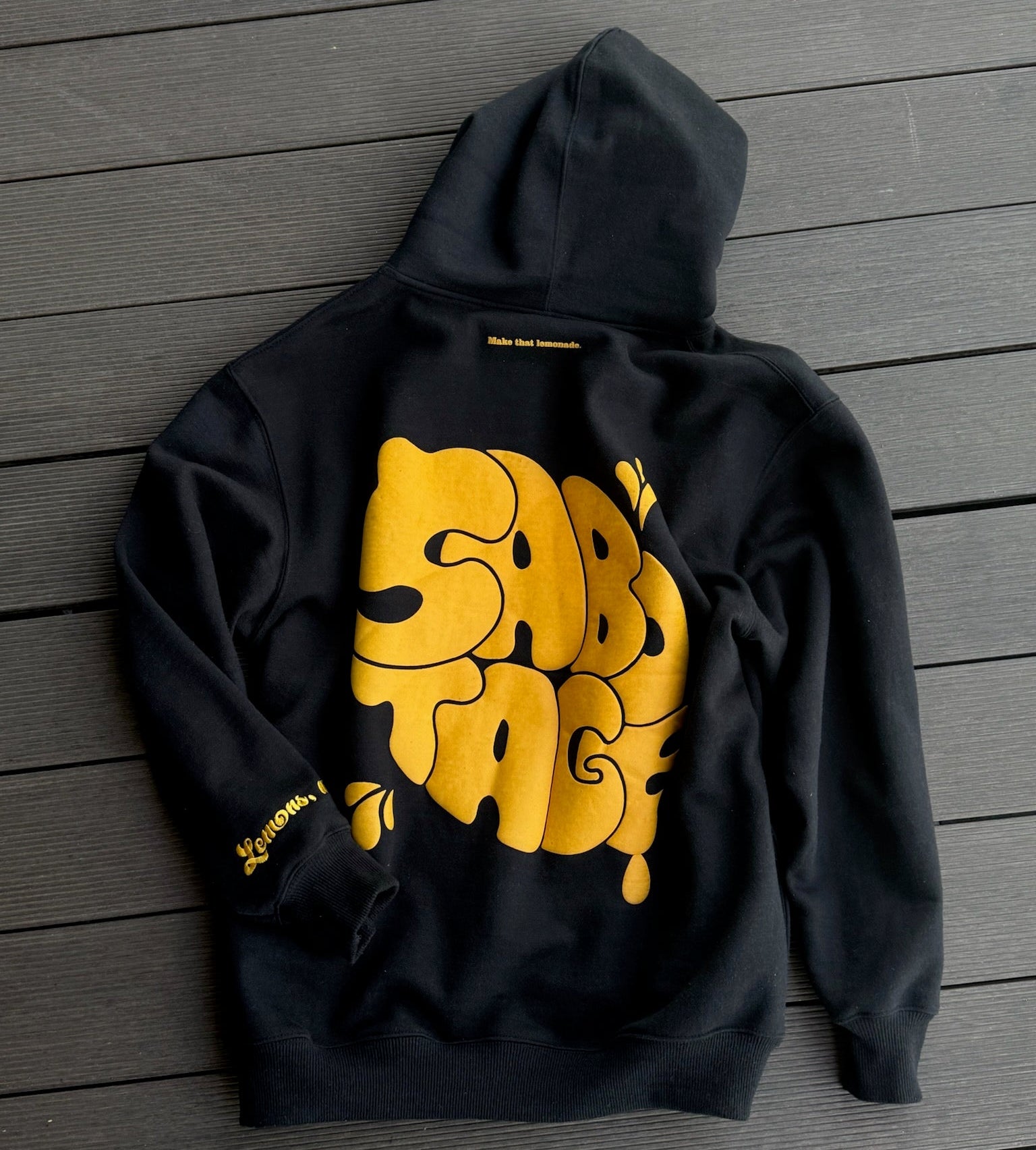 Black hoodie with yellow graphic design on a wooden surface