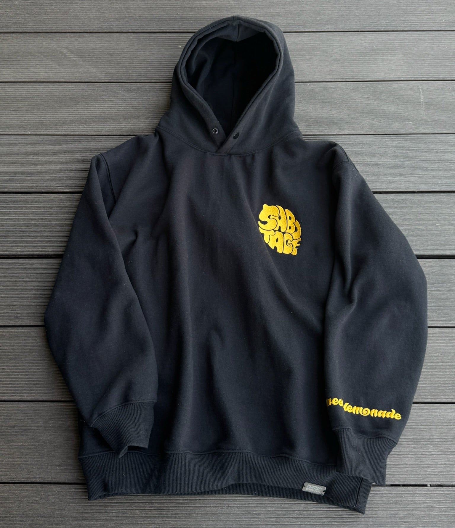 Black hoodie with yellow graphic design on a wooden surface