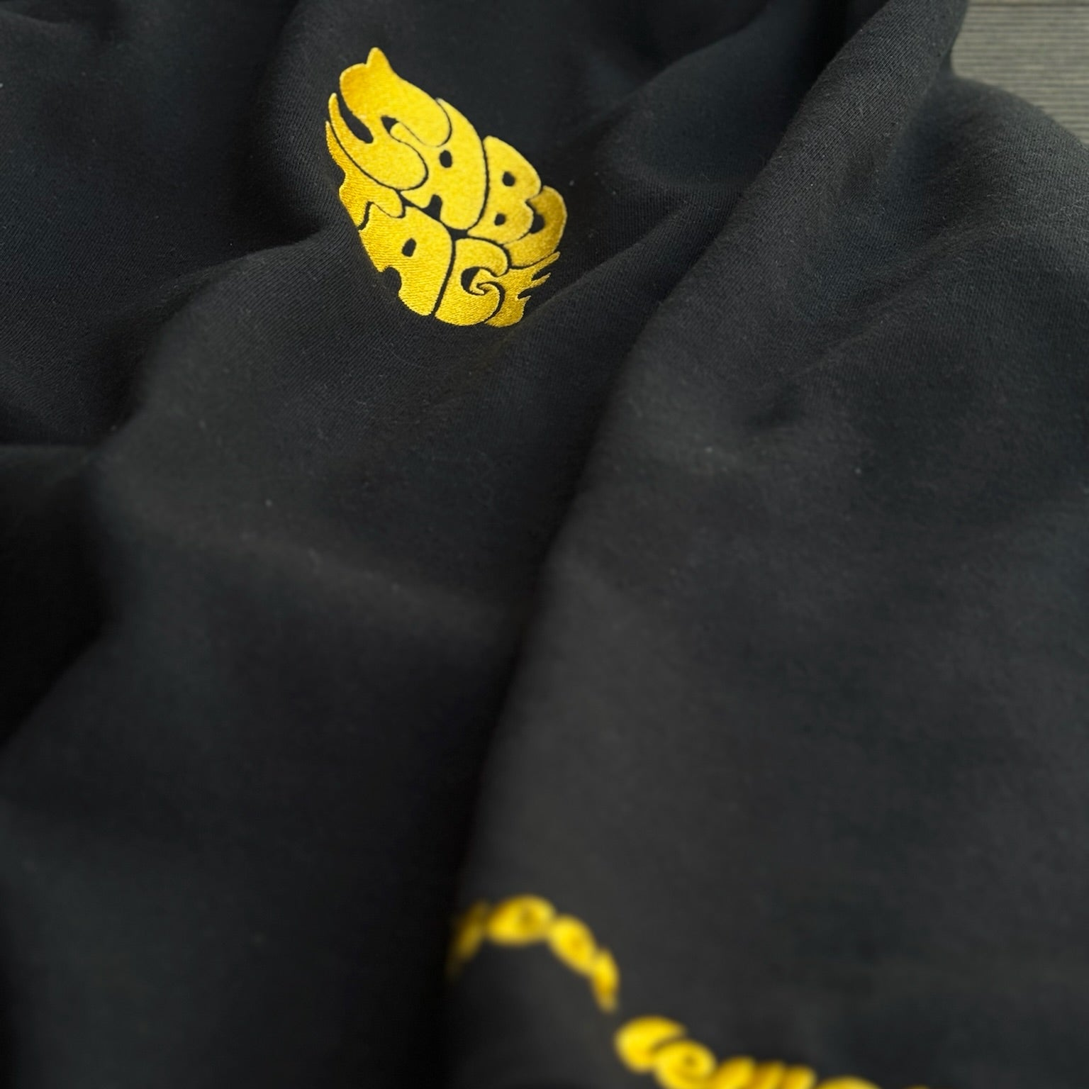 Black fabric with yellow embroidery on a gray background