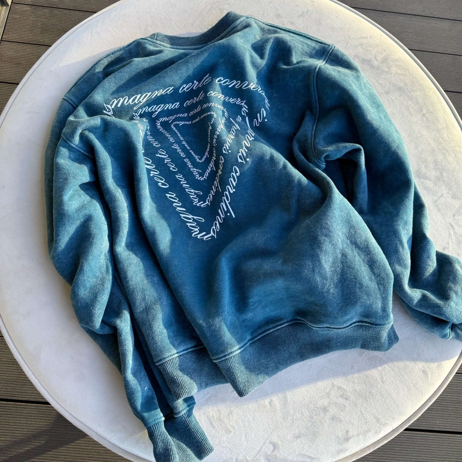 Blue sweatshirt with text on a white plate on a wooden surface