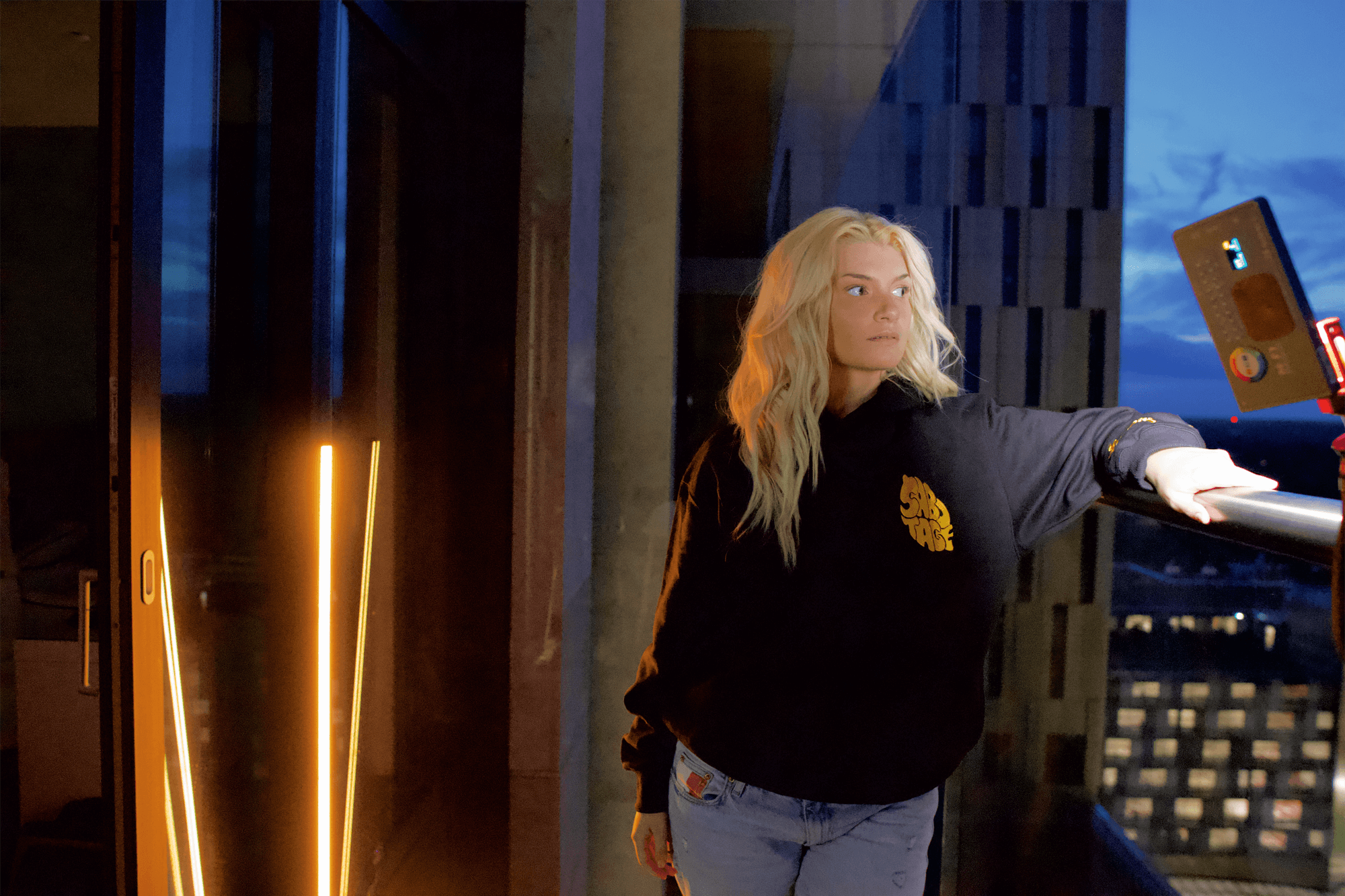 Back shot of man wearing a black hoodie with yellow puff print writing